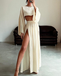 Person wearing a beige outfit with a high slit in a minimalistic room.