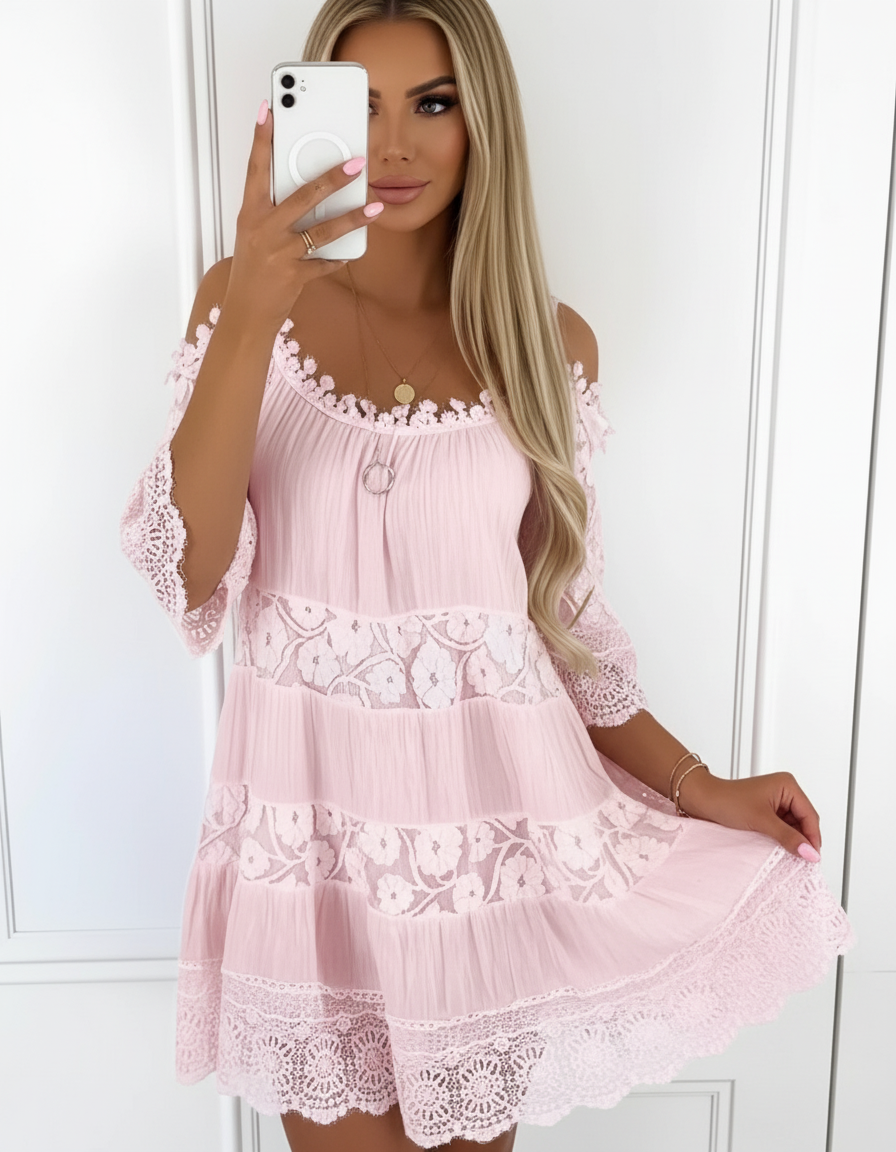 Woman wearing a pink lace dress taking a mirror selfie.