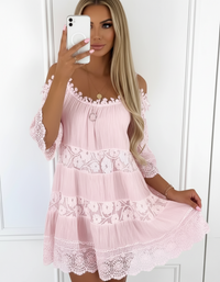 Woman wearing a pink lace dress taking a mirror selfie.