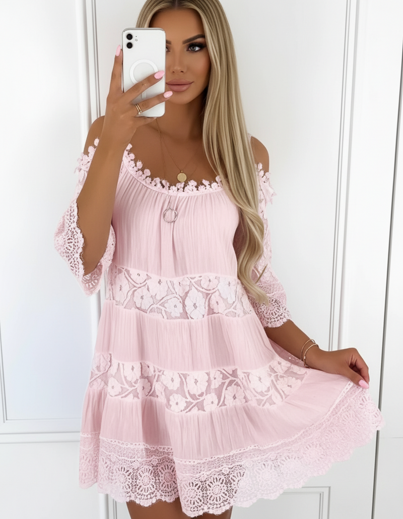 Woman wearing a pink lace dress taking a mirror selfie.