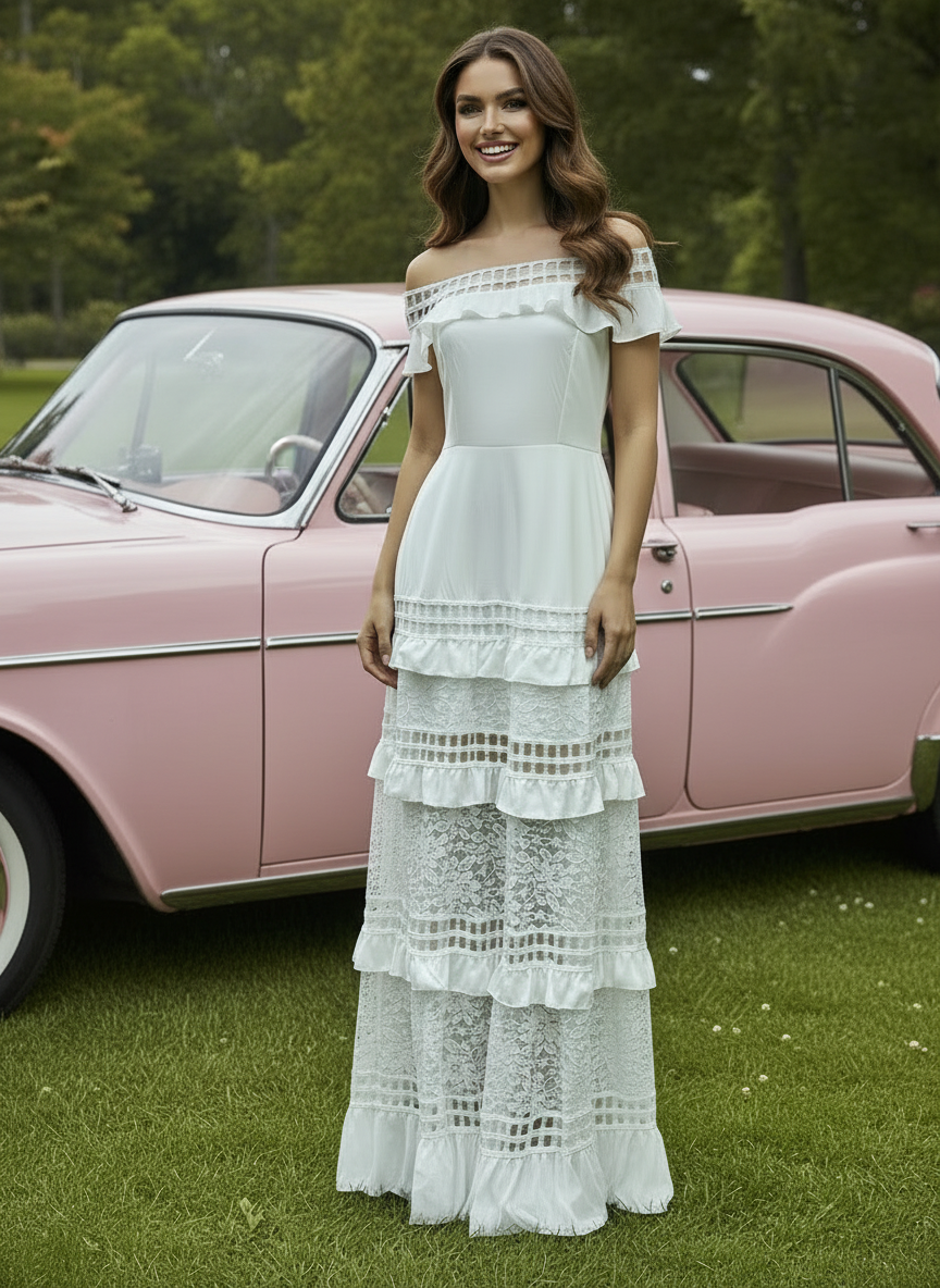Woman in a white Alexa lace dress standing in front of a pink vintage car on grass.