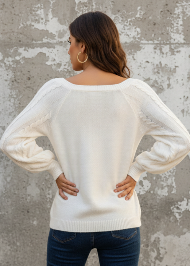 Woman wearing Anya white sweater with sheer sleeves against a beige wall.