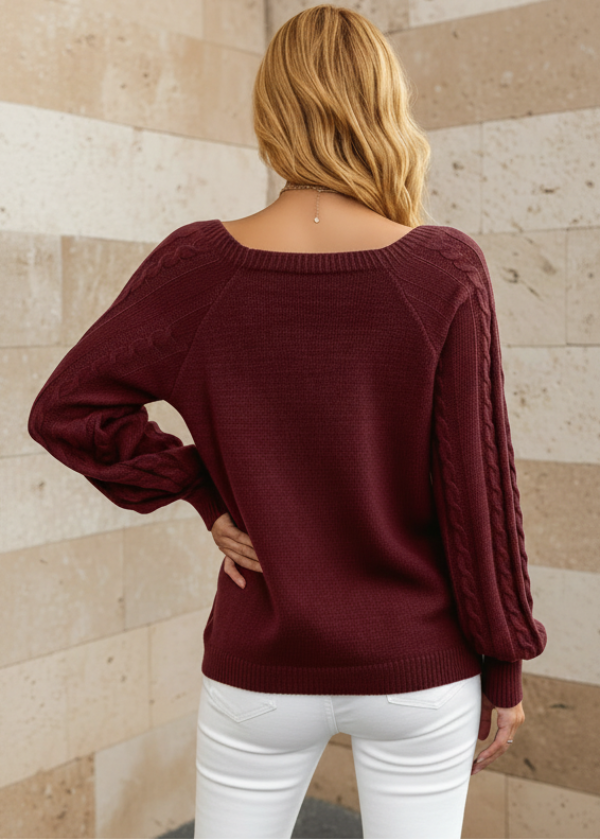 Person wearing Anya burgundy sweater with a neutral stone wall background