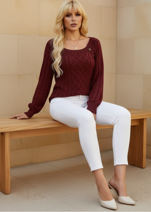 Woman sitting on a wicker chair wearing Anya burgundy sweater and white pants.