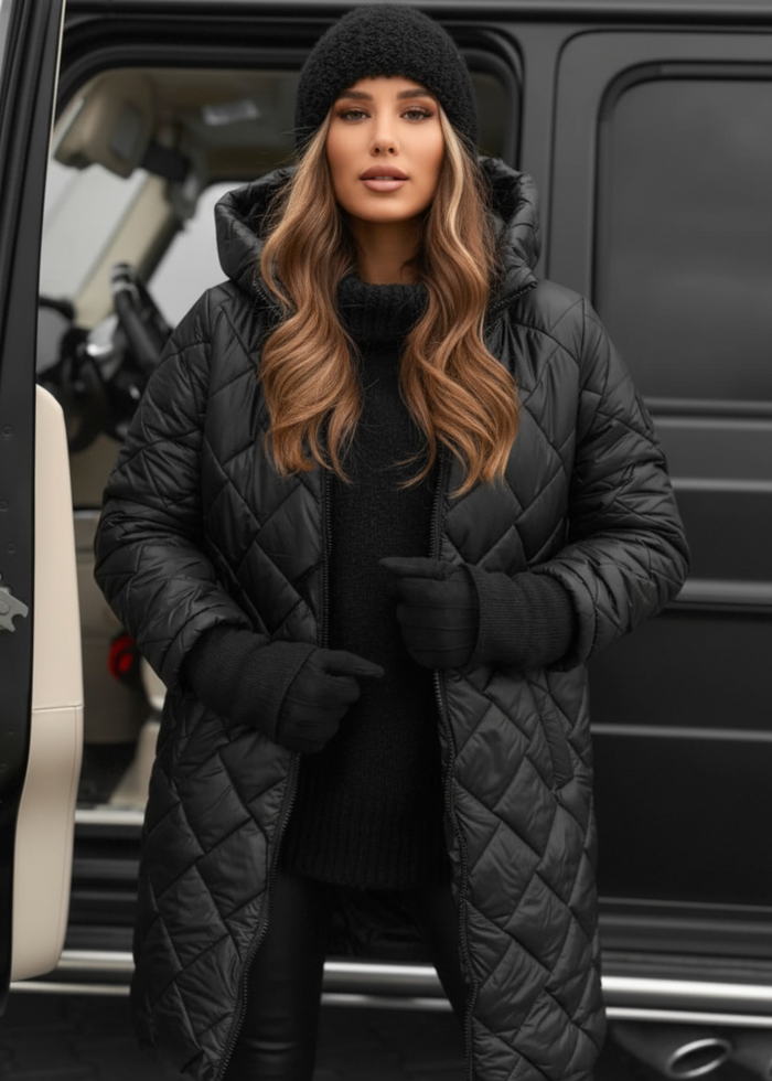Woman wearing a black quilted coat and hat standing next to a vehicle.