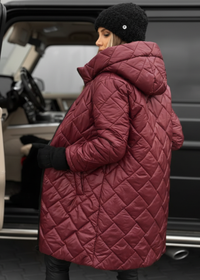 Person wearing a quilted pink coat standing next to a car