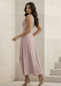 Woman in a Chelsea dusty pink dress standing against a light-colored wall.