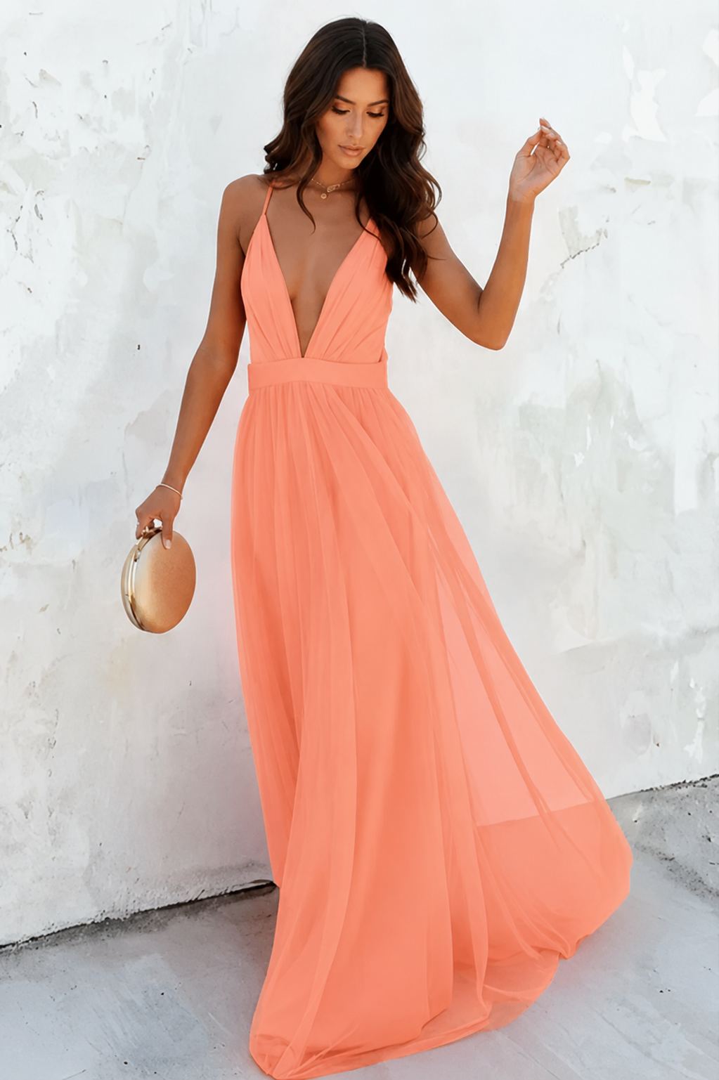 Woman wearing a long peach dress against a white background