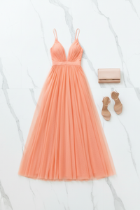 Peach-colored dress with matching clutch and shoes on a white background