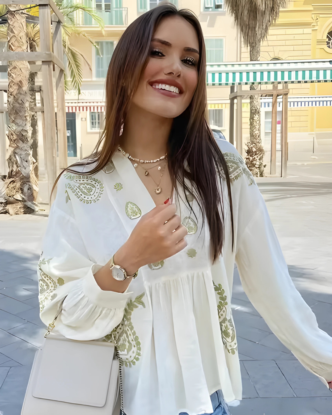 Woman wearing a VV white embroidered top with green patterns outdoors.