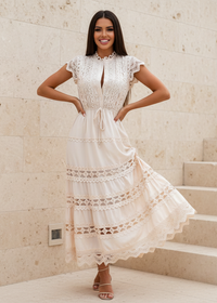 Woman wearing Dani Beige lace dress standing on stone steps.
