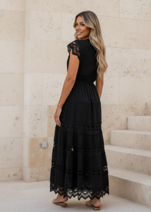 Woman wearing Danni black lace dress standing on stone steps.