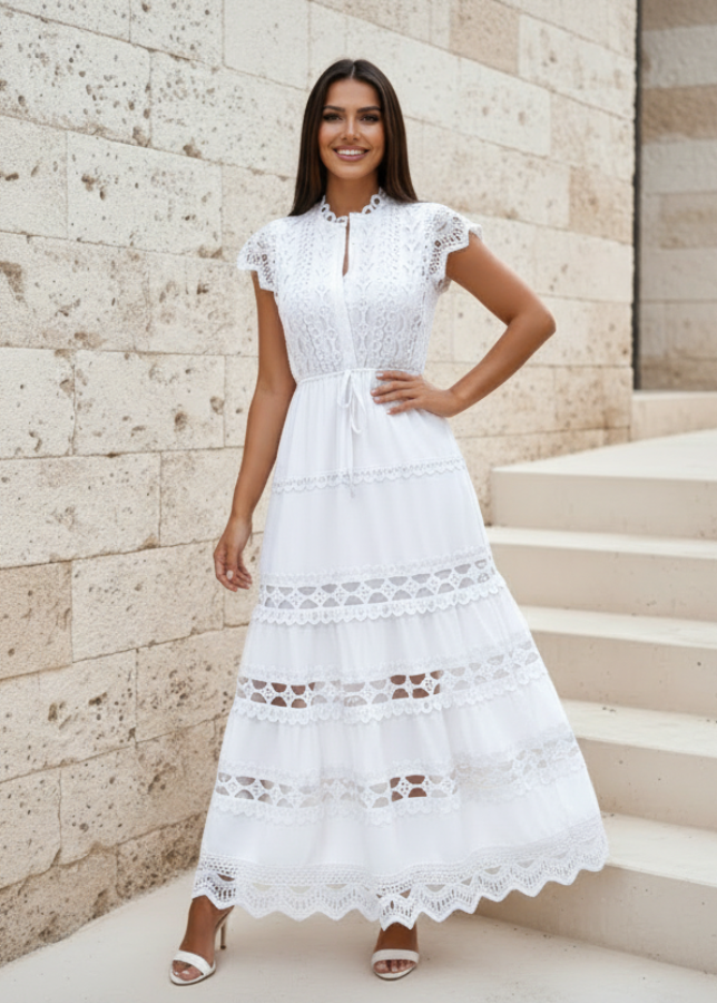 Woman wearing Danni white lace dress standing on stone steps with a stone wall background
