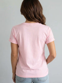 A woman viewed from behind wearing a Villa Vibes Designer Inspired light pink short-sleeve t-shirt and light blue jeans against a plain light gray background.