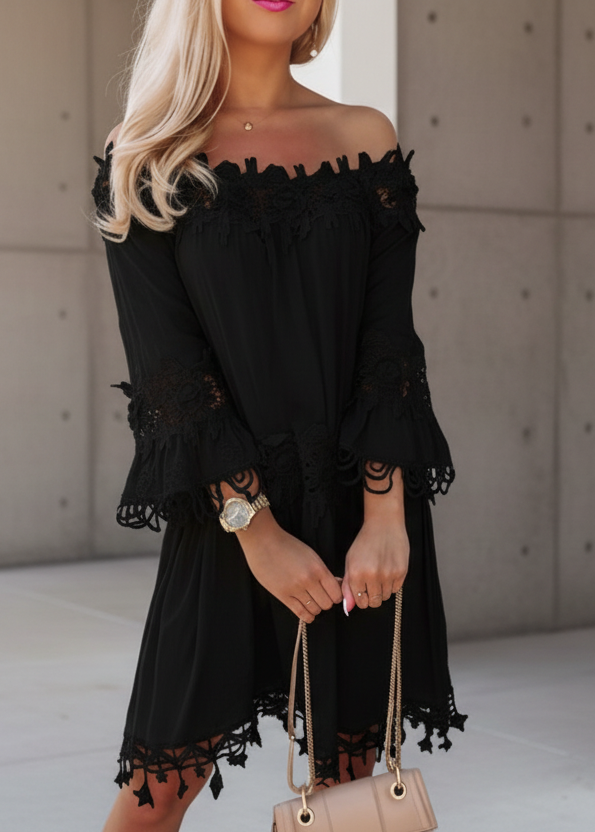 Woman in a black Diaz dress against a stone wall.