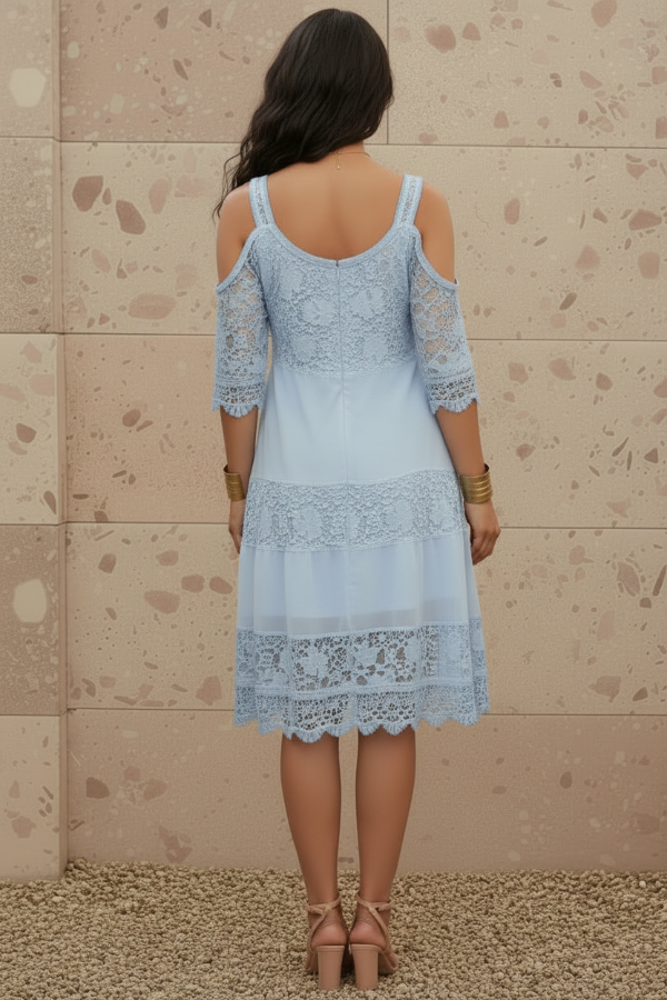 Woman wearing Ella light blue lace dress against a beige wall.
