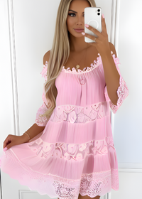 Woman wearing a pink lace Fallon dress from Villa Vibes standing in front of a white plastered wall 