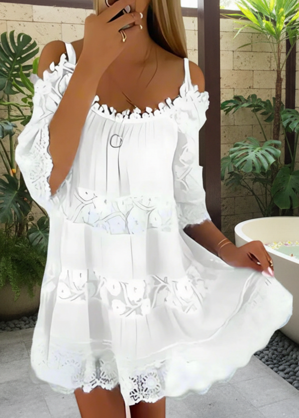 White Fallon lace dress worn by a person against a gray brick wall.