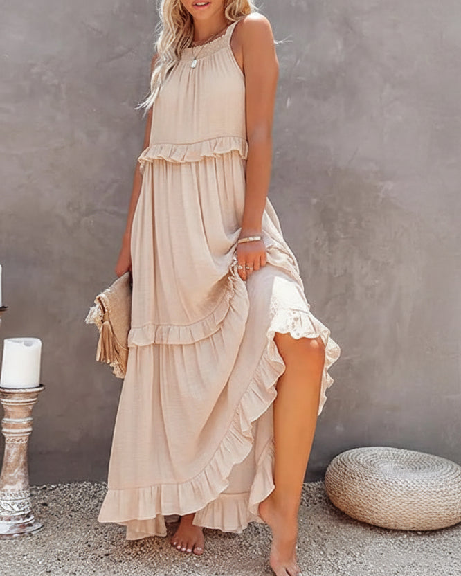 Woman wearing a beige dress against a gray wall.