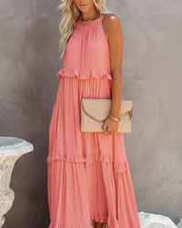 Woman wearing a pink dress holding a beige clutch against a neutral background