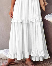 White ruffled white dress worn by a person on a neutral background