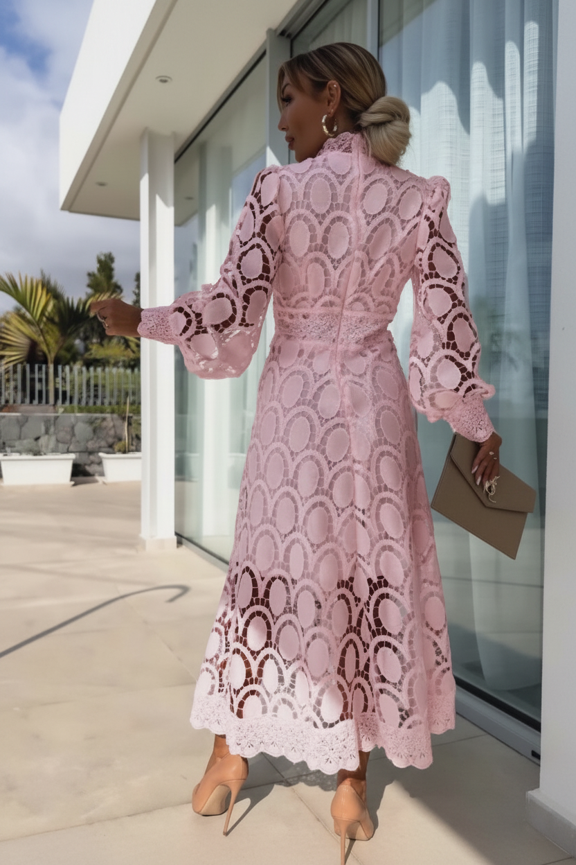 Woman wearing Villa Vibes pale pink lace dress standing outside a modern building.