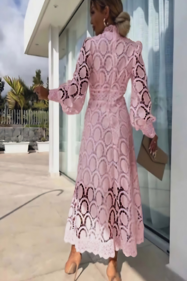 Woman wearing Villa Vibes pale pink lace dress standing outside a modern building.