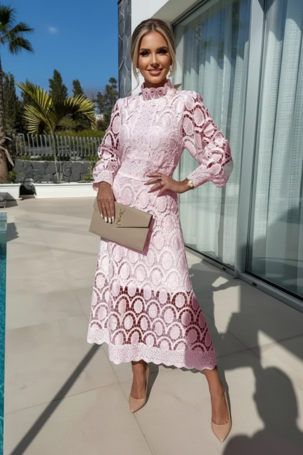 Woman in Villa Vibes pale pink lace dress standing by a poolside.