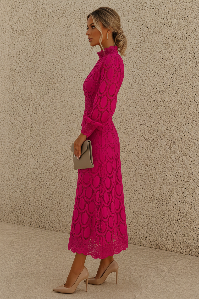 A woman in profile wearing a bright pink long-sleeve midi dress with a circular lace pattern, holding a small taupe clutch and wearing beige heels, standing against a textured beige wall.