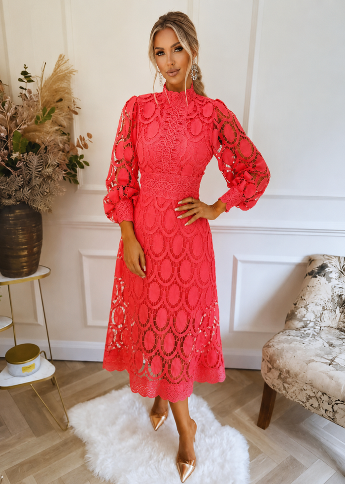 Woman wearing a pink lace dress in an elegant room setting.