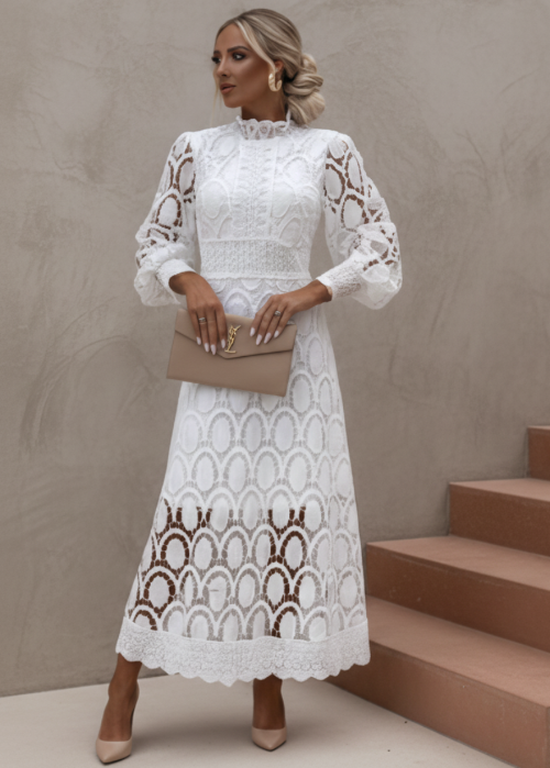 Woman wearing a white Jasmine lace dress standing on steps with a neutral background