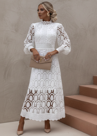 Woman wearing a white Jasmine lace dress standing on steps with a neutral background