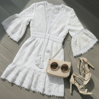 White lace dress with beige handbag and shoes on a wooden floor