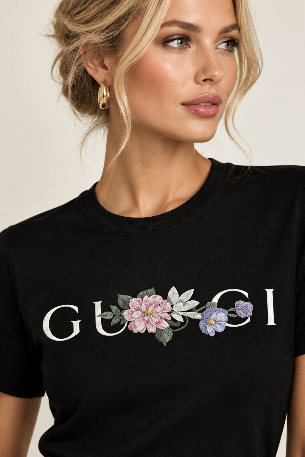 A close-up of a woman wearing a black crewneck t-shirt with a floral embroidered design and the word 'GU8CI' in white across the chest.