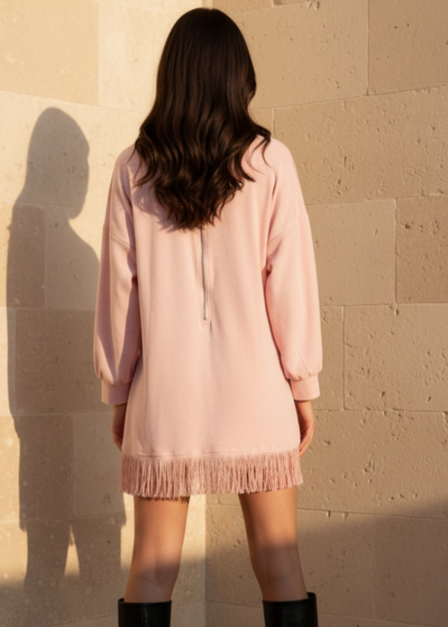 Woman wearing Maddox pink dress and black knee-high boots against a beige stone wall.