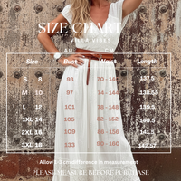 Woman wearing Naiya white dress with a size chart overlay on a textured wall background