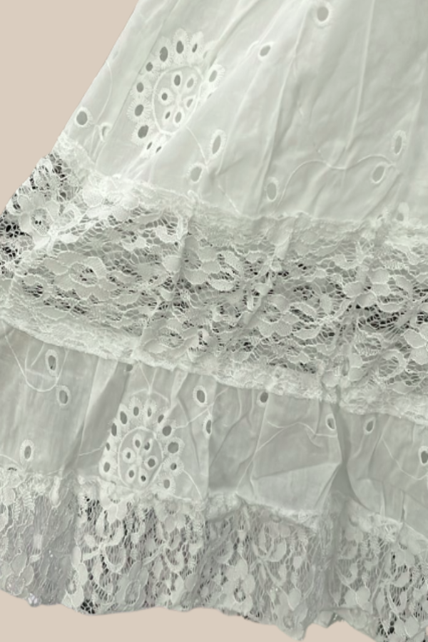 Close-up of Naiya white lace fabric with intricate patterns on a light pink background