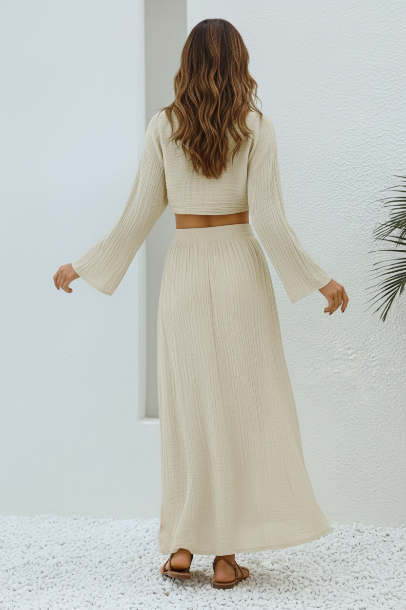 Woman wearing a Paloma beige long-sleeve top and skirt set against a white wall.