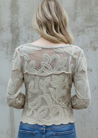 Person wearing Roxy beige lace top against a concrete wall