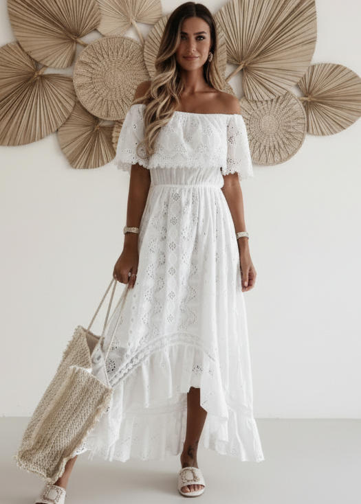 Woman in a white lace Rumer dress standing against a wall with decorative fans.