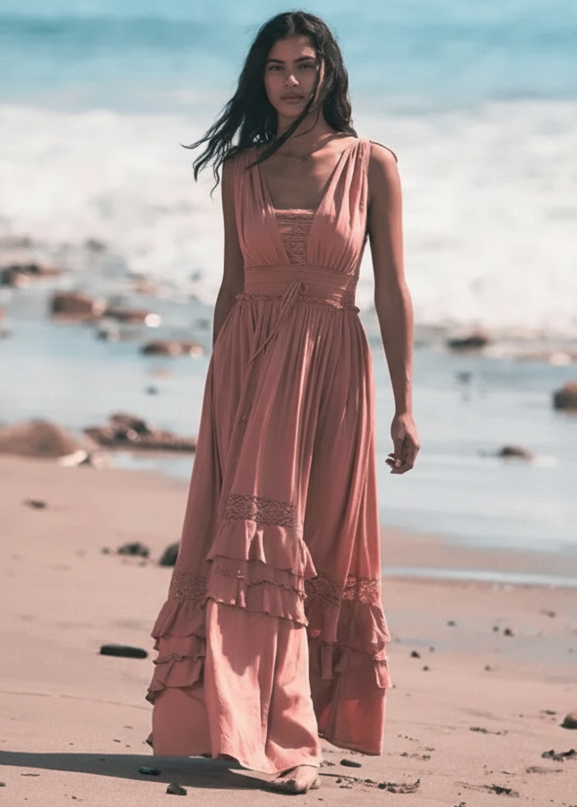 Woman in a pink Shakira dress standing on a beach with ocean in the background