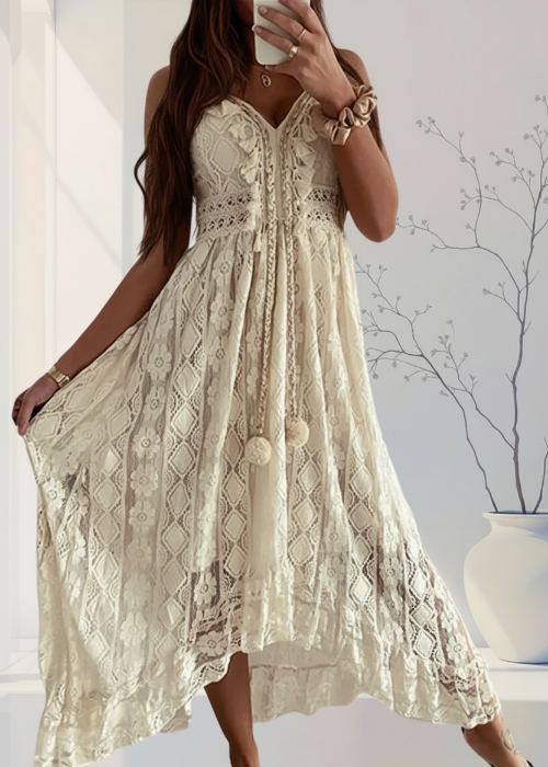 Woman wearing a beige lace dress with tassels indoors.