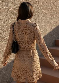 Woman wearing Sienna beige crochet dress against a textured wall.