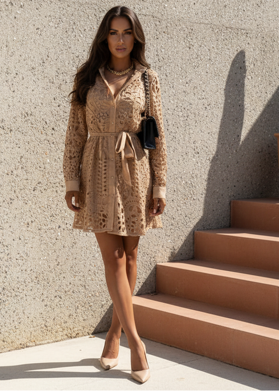 Woman in Sienna beige lace dress standing on steps against a textured wall.