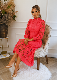 Woman in a pink dress sitting on a chair in an elegant room.
