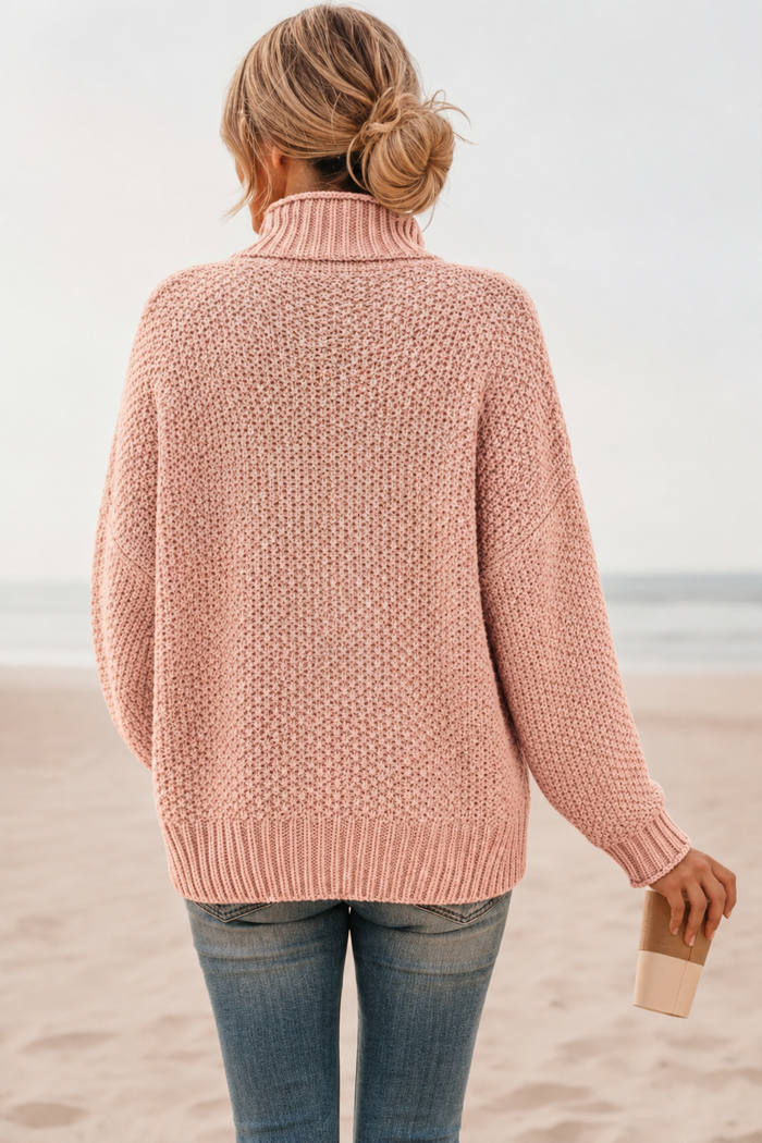 Person wearing a Skye pink sweater on a beach