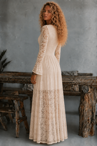 Woman wearing Tessa cream lace dress from Villa Vibes standing in front of rustic furniture