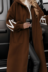 Person wearing a Villa Vibes Kelly brown coat with white accents, holding a black coffee cup, standing next to a vehicle.