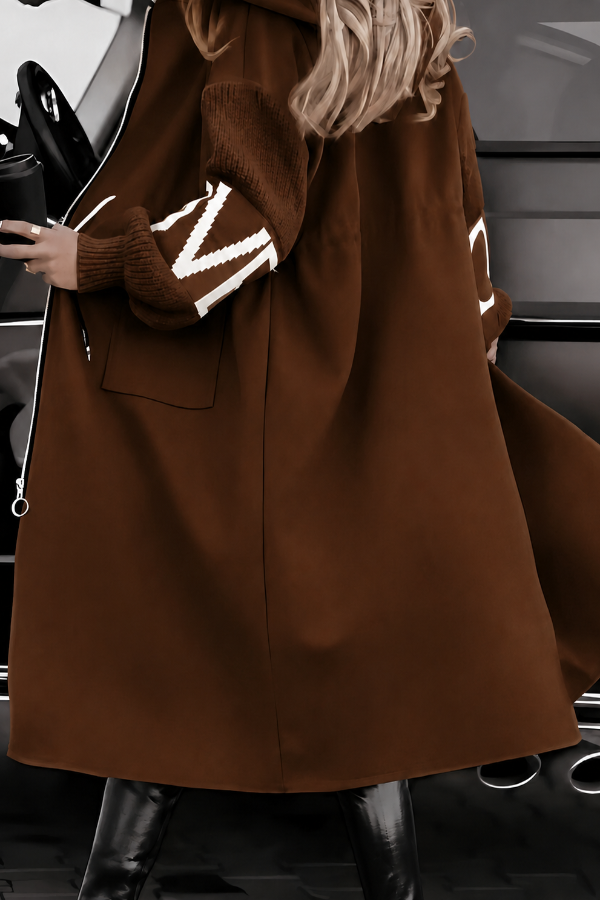 Villa Vibes Kelly Brown coat with white lettering worn by a person, with a blurred background