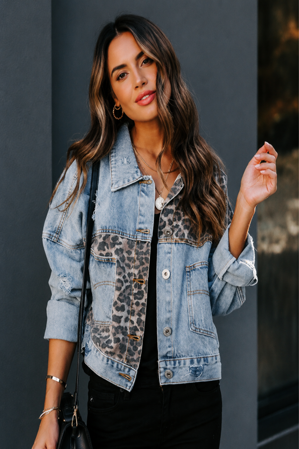 Woman wearing a Villa Vibes Kia Denim Trucker Jacket with leopard print accents against a dark background